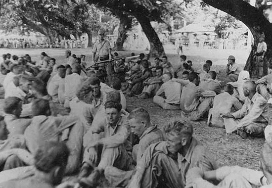 Bataan Death March: Group of American prisoners, note Japanese guard with fixed bayonet. The March of Death was from Bataan to the prison camp march at Cabana Tuan. May 1942.